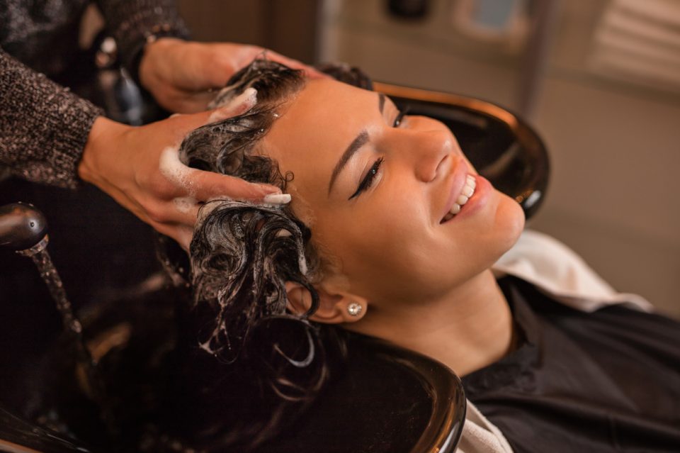 Smiling woman in hair salon washing hair.