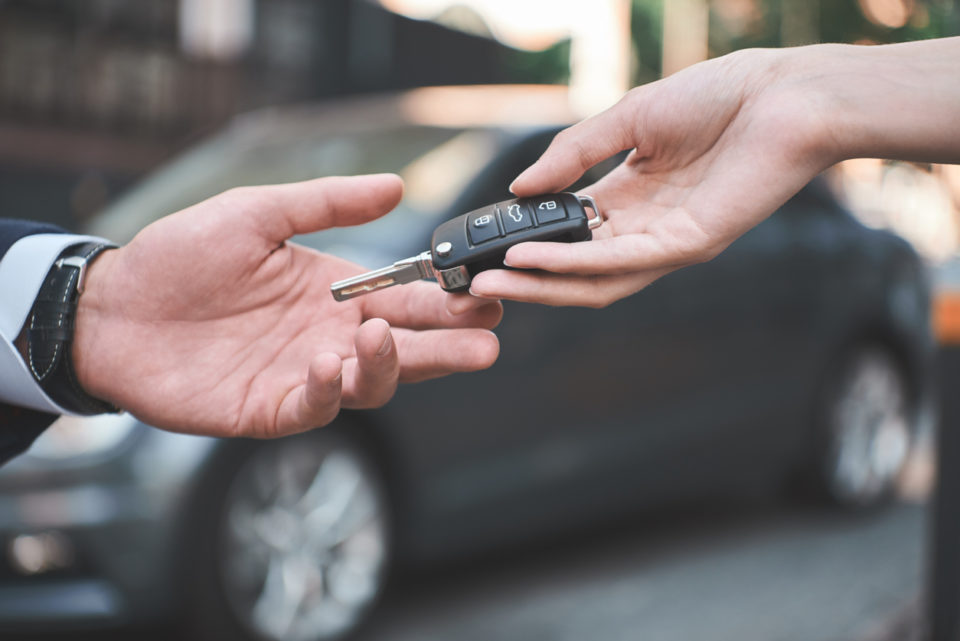 Young man receiving car key from saleswoman.