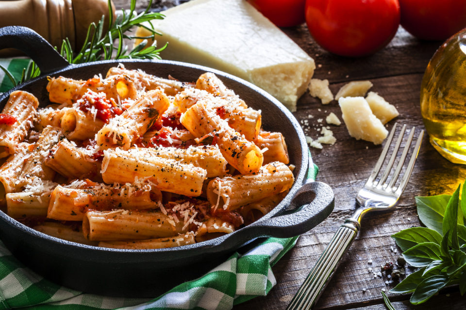 Pasta in a cast iron pan shot on rustic wooden table