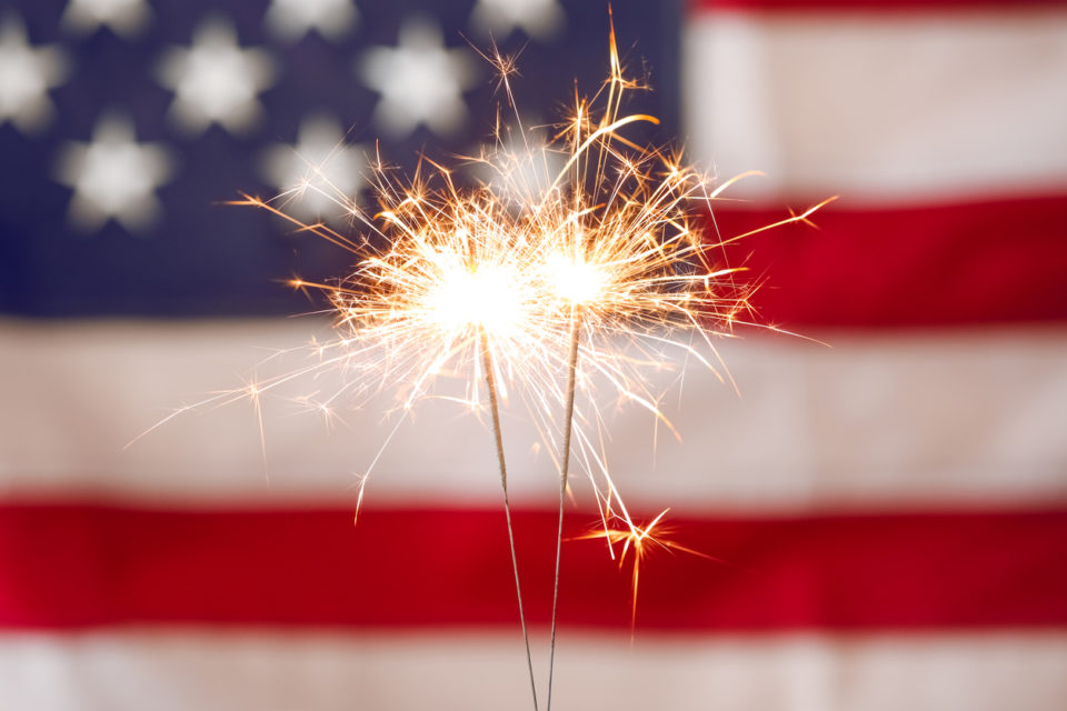 Bright burning sparklers against American flag, closeup