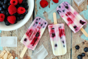 Group of homemade mixed berry popsicles on a rustic wood background