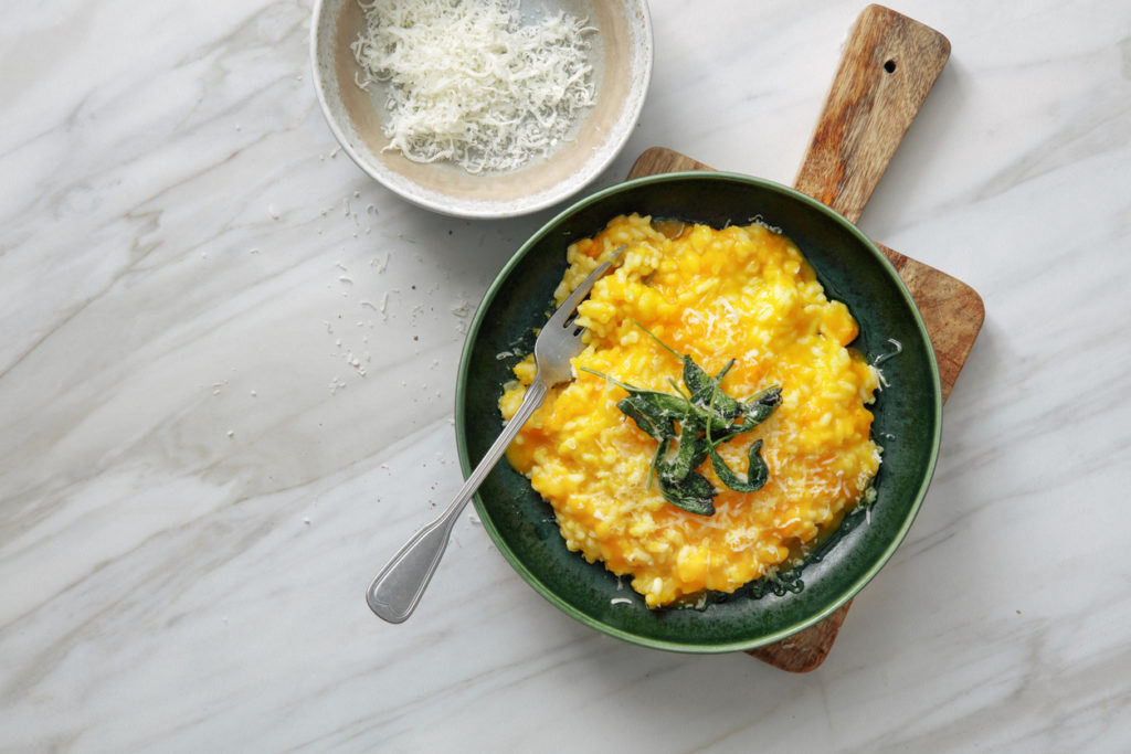 Creamy Baked Pumpkin Risotto with sage on marble background. Top view.