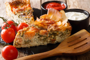 Delicious pie stuffed with salmon, tomatoes, cheese and herbs close-up. horizontal