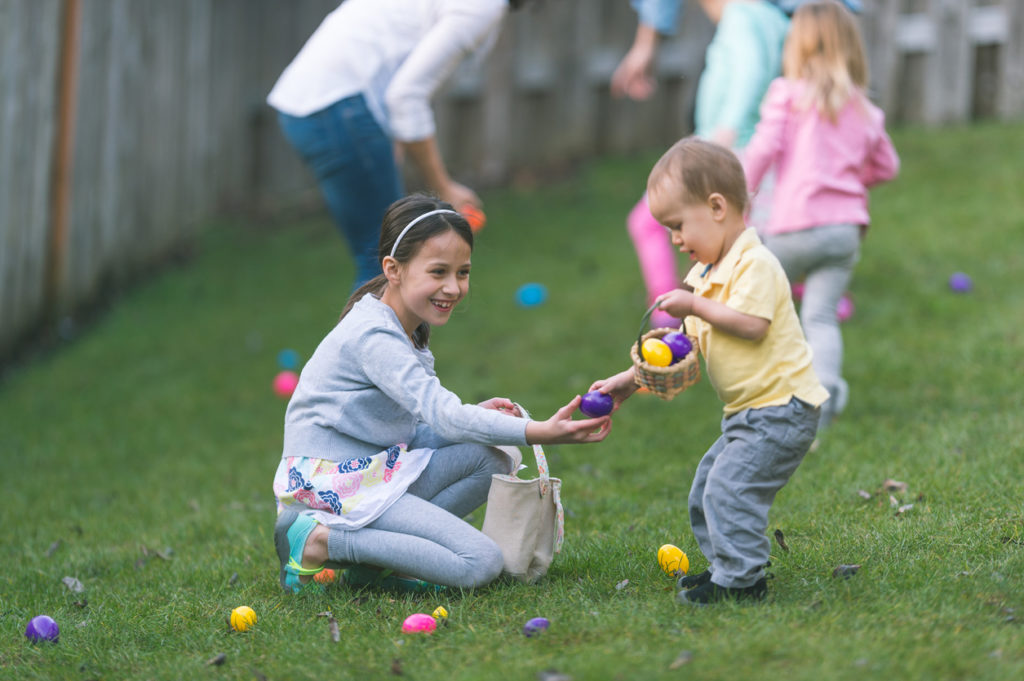 Big sister helps little brother collect Easter eggs